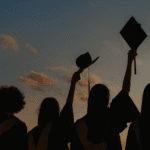 Wisudawan mengangkat topi toga, simbol kelulusan melalui student loan